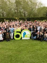 Large group gathered around colourful 50th anniversary letters