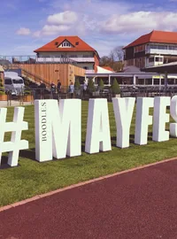 Large white MAYFEST hashtag letters beside a running track