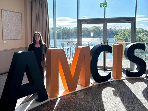 Woman standing behind large freestanding AMCIS conference letters
