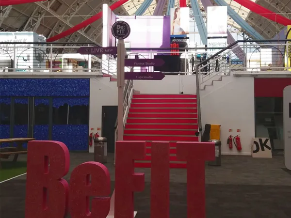 Large Be:FIT letters and suspended event branding inside a venue