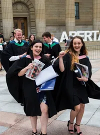 Graduates beside Abertay University letters