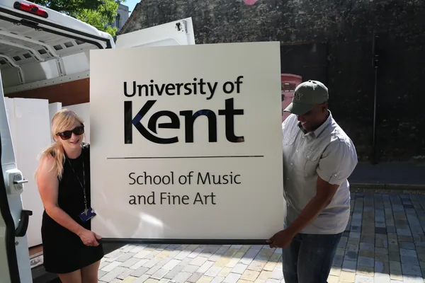 Two people carrying a large University of Kent display panel