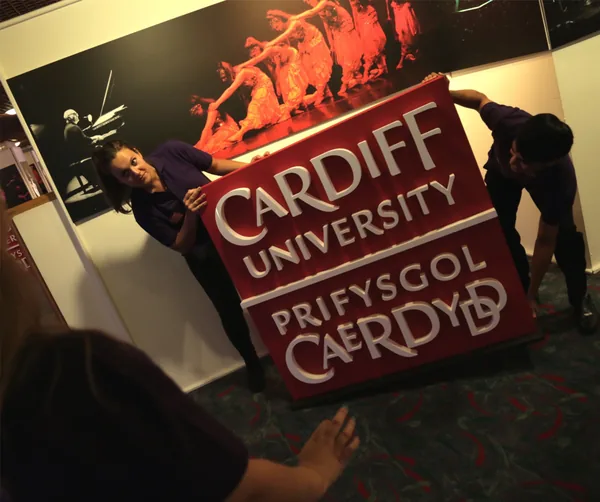 People positioning a large freestanding university logo