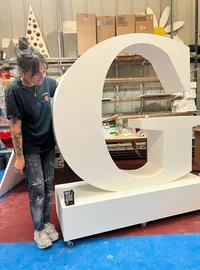 Large freestanding G letter with a member of the workshop team