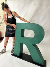 Workshop team member beside a large green freestanding R letter