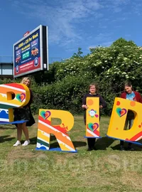 People standing with colourful freestanding PRIDE letters