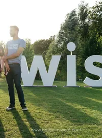 Visitors standing beside large white WISE festival letters outdoors