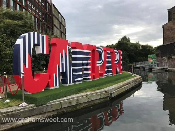 Large red, white and blue freestanding Campari letters beside a canal
