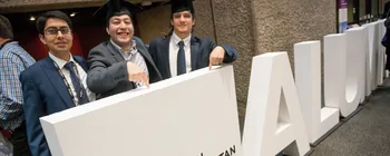 Graduates posing with large white ALUMNI letters for London Metropolitan University