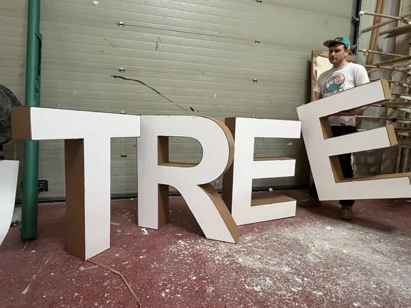 Workshop team member handling large paper-based display letters