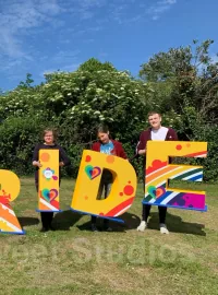 People holding colourful Aviva Pride display letters
