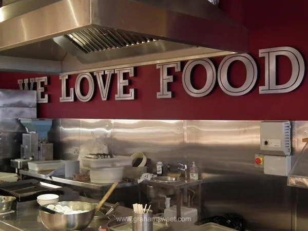 Raised We Love Food letters mounted above a retail food counter