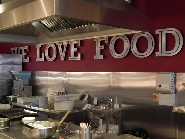Large LOVE FOOD letters installed above a commercial kitchen counter