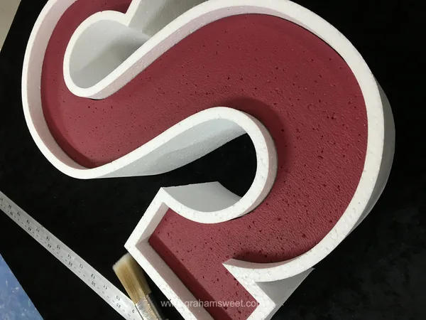 Close-up of a polystyrene letter with a burgundy painted face and white sides