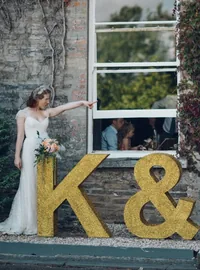 Bride beside large gold glitter K and M wedding initials