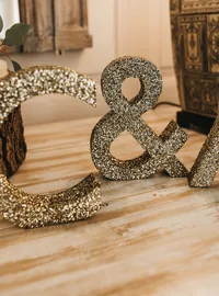 Small gold glitter initials arranged beside wedding table decorations