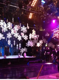 Large white snowflakes suspended across a winter event stage