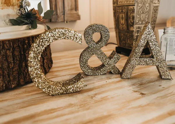 Small gold glitter initials arranged on a wedding styling table