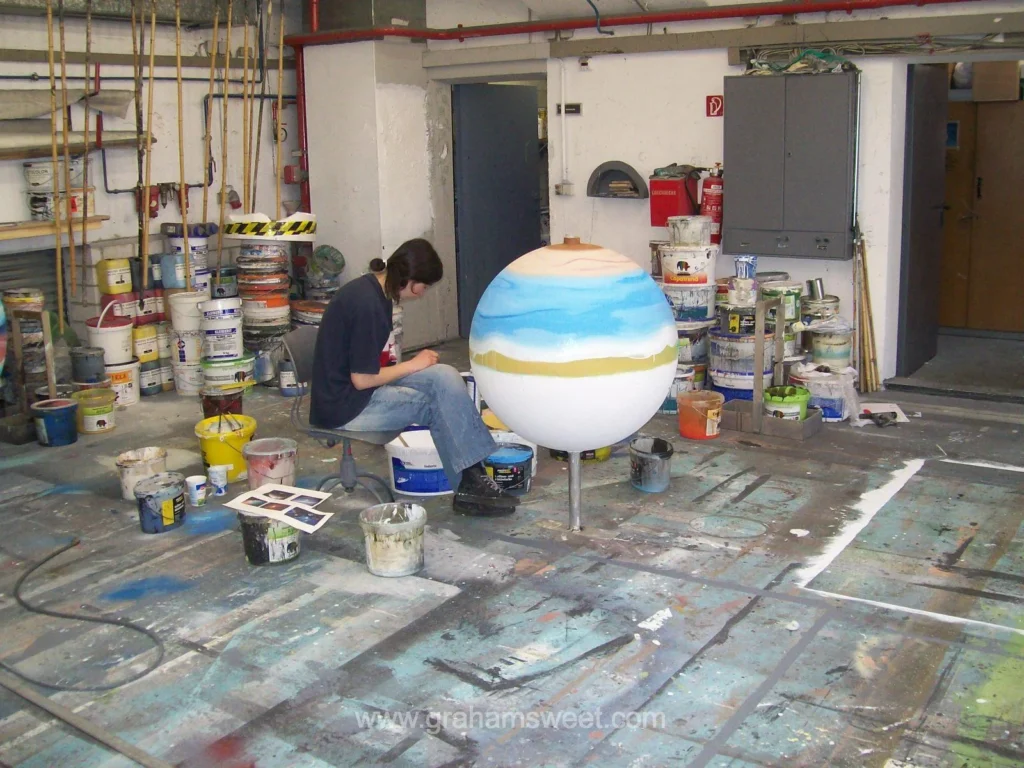 Theater Koblenz scenic artist painting a large polystyrene sphere as a planet