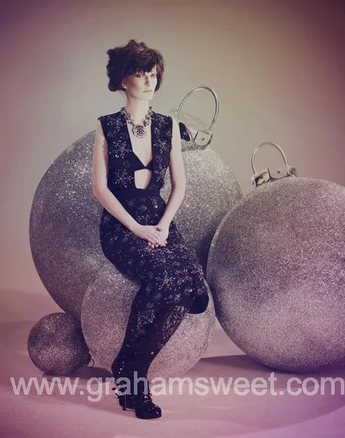 Model seated among silver glitter baubles of different sizes