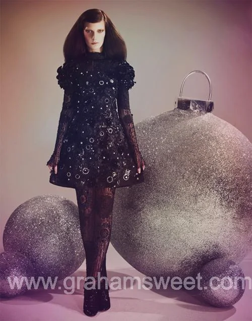 Model beside large silver glitter baubles in the magazine fashion shoot