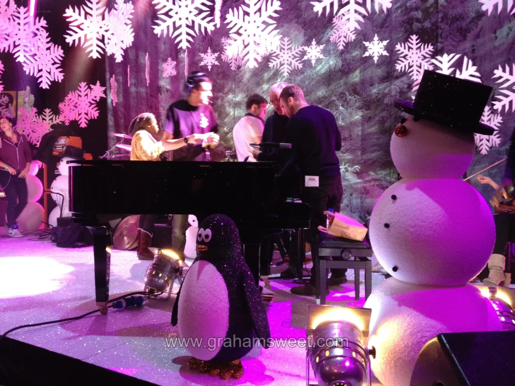 Performers surrounded by snowflakes and snowmen on the Christmas set