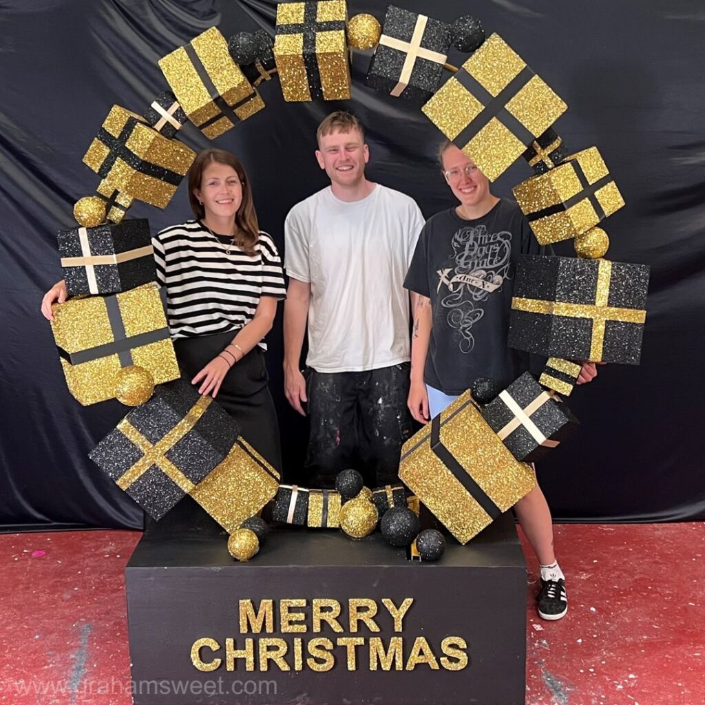 Staff standing inside an oversized Christmas Present Ring photo prop