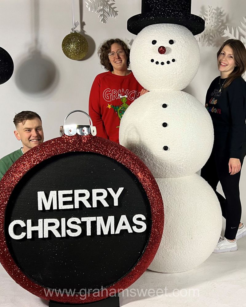 Staff beside a giant snowman and Merry Christmas bauble photo prop
