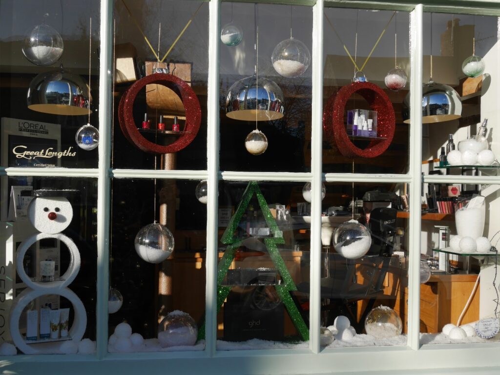 Festive salon window with red bauble shelves, silver decorations and a snowman display