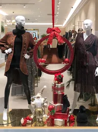 Christmas retail window with mannequins and a large hanging decoration