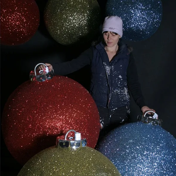 Woman standing among large red, gold and blue glitter baubles