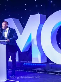 Speaker beside large MC letters on stage